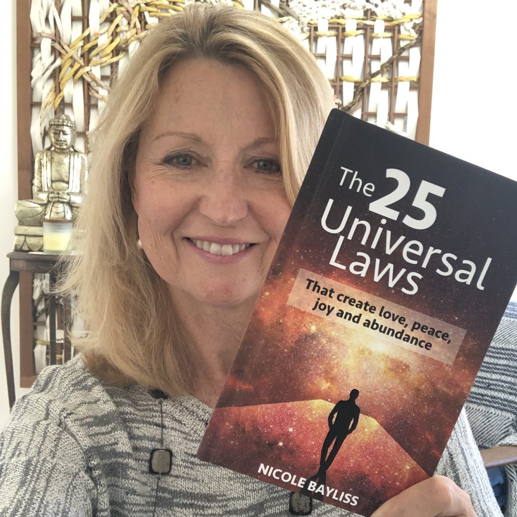 Nicole Bayliss smiling holding a copy of the book 25 Universal Laws